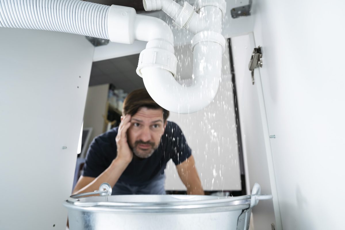Homeowner with a leaking pipe under the sink