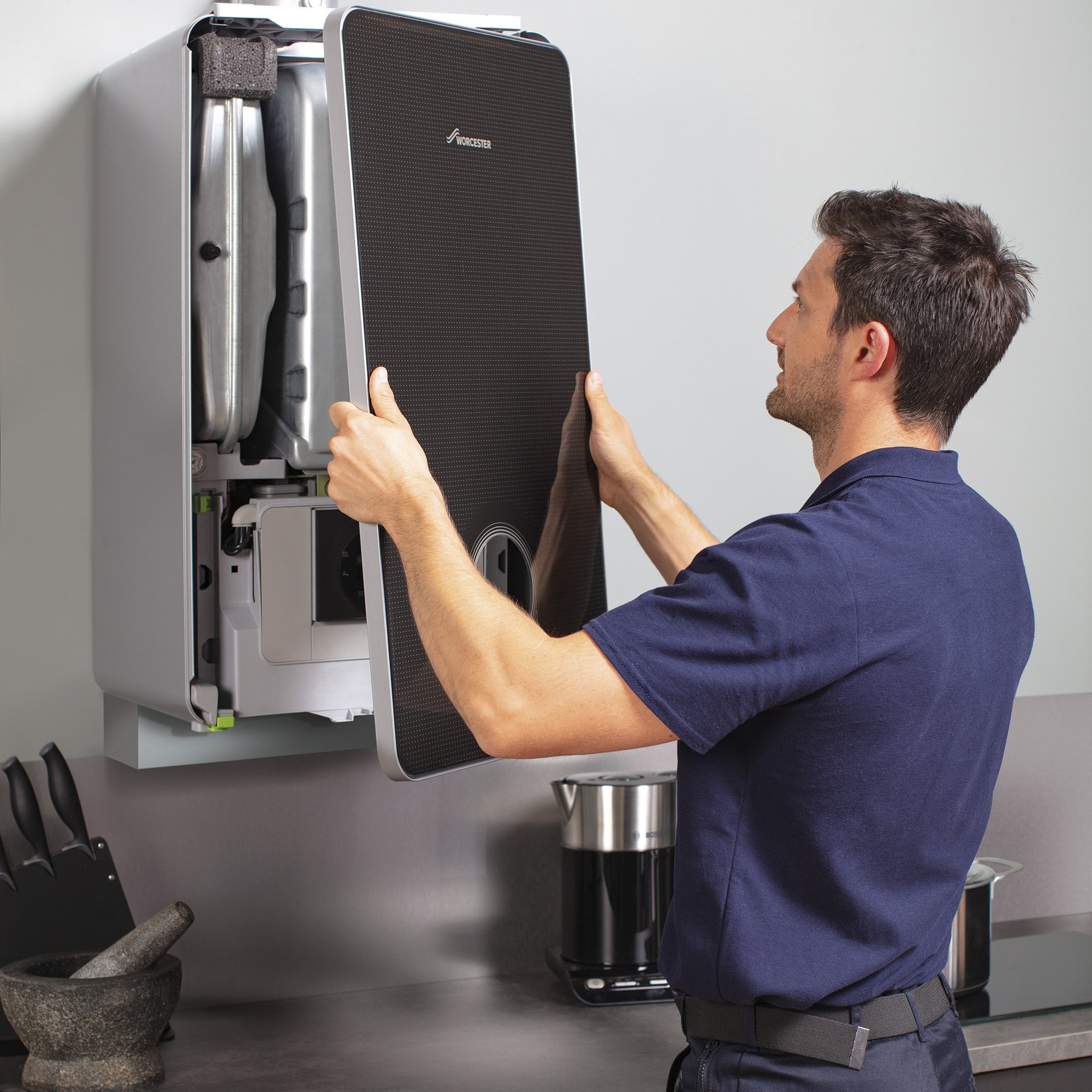 Engineer fitting the front panel onto a new boiler